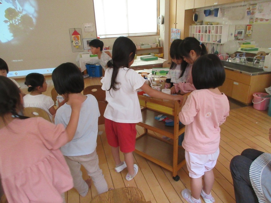 雨の日限定オープンの「まんげきょうえいがかん」。参観日に作った万華鏡の映像をプロジェクターで壁に大きく映し出したのを見て、「えいがかんみたい」とあるお友だちがつぶやいたことから始まった遊びです。「どんなものがあるかな?」「どんなばしょがあるかな?」とみんなの行ったことのある映画館を思い出しながら遊びを繰り返しています。千切れるチケットがあったり、食べ物と飲み物はワゴン車で販売してみたり…「もっとたのしいえいがかんになるには?」をキーワードに遊びをどんどん変化させていきたいと思っています。