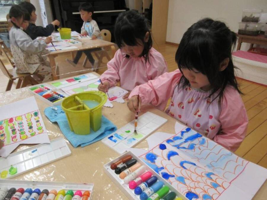 ”きれいな色のうろこだね” 鯉のぼりの模様や園庭の花々の絵を絵の具を使って塗りました。色が交じらないように、離れた場所を選んで塗ったり、なるべくはみ出さないように気をつけたりしながら塗りました。また、「紫ってどうやって作るのかな?」自分で試しながら、新しい色が生まれる面白さも味わっていました。