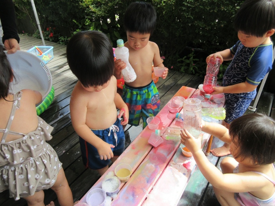 暑い日が続き、水遊びを毎日のように楽しむ子ども達です♪色水を使って遊ぶと、ジュース屋さんが始まりました!赤・黄・青…色んな色を混ぜると違う色に変わって、それを陽の光に当てるとキラキラ光っていろんな不思議を体験しながらの水遊びとなりました☆