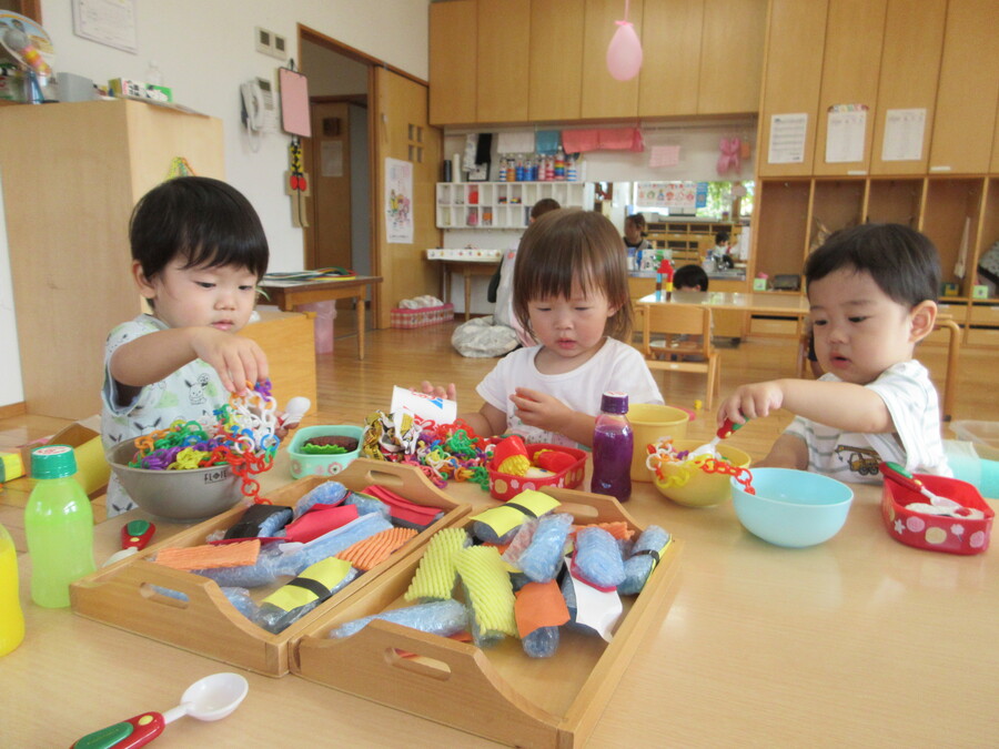 テーブルにたくさんの美味しそうなごちそう!食べる真似をしながら隣のお皿に移し替えています。長くつながったチェーンはうまく乗せないと重みで流れ落ちてしまいます。「なんで落ちちゃうんだろう⁉」遊びの中で失敗と成功を繰り返しながら夢中になっていました。