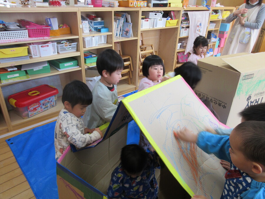 ”できたよ!たんぽぽハウス、つくしハウス”クレヨンでぬりぬり…いつもの画用紙とは違ってガタガタしてる感触や広い面に描くことが新鮮だったようです。出来上がると、仲良くお家に入って、「トントントン何の音?」「新幹線の音!」とお友だちや先生とやり取りを楽しんでいました。