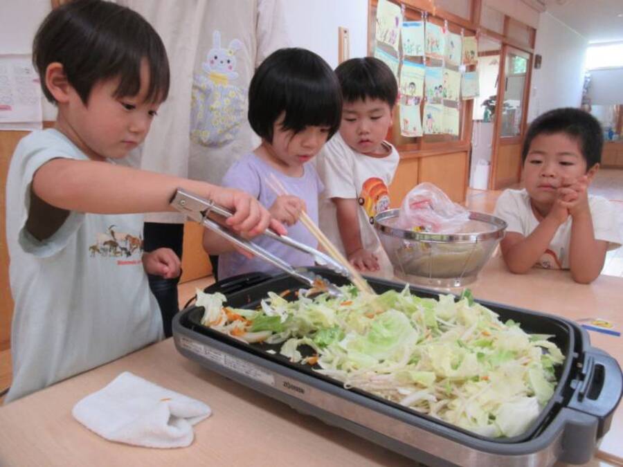 ばら組さんとグループごとにホットプレートを囲んで焼きそばクッキング!囲んで食べるからか子どもたちは「焼きそば“パーティー”楽しみ♪」と言ってワクワク!皮むきも少しずつ手馴れてきました。「あっ!ジューって聞こえてきたよ」「なんかいい匂いしてきた。早く食べたいな~」と野菜やお肉の焼ける匂いや音を目の前で感じながら代わりばんこに焼いて、さあ出来上がり♪みんなでいただきまーす♪たくさんおかわりしました。